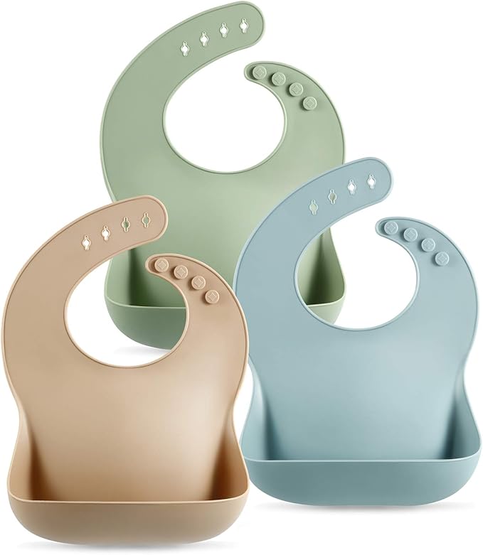Three silicone baby bibs in soft colors: green, blue, and beige, featuring a scoop pocket for catching food spills.