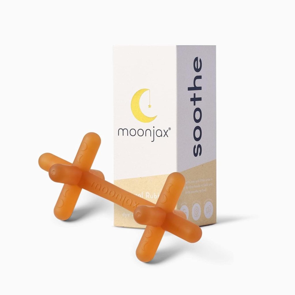 A soothing rubber toy by Moonjax, shaped like a cross, with a vibrant orange color next to its packaging labeled 'soothe'.